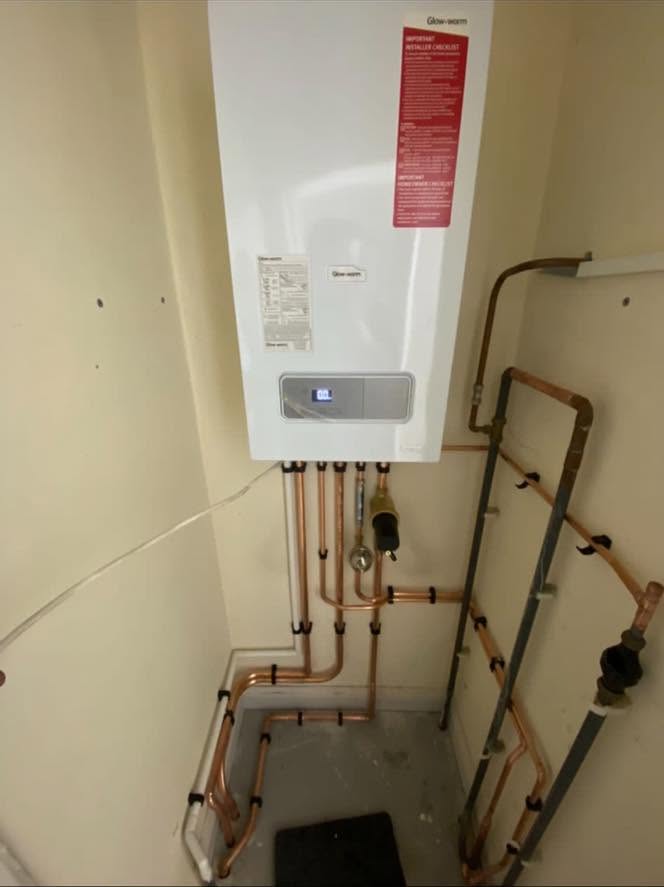 A new combi boiler fitted in a cupboard, with new copper pipework below