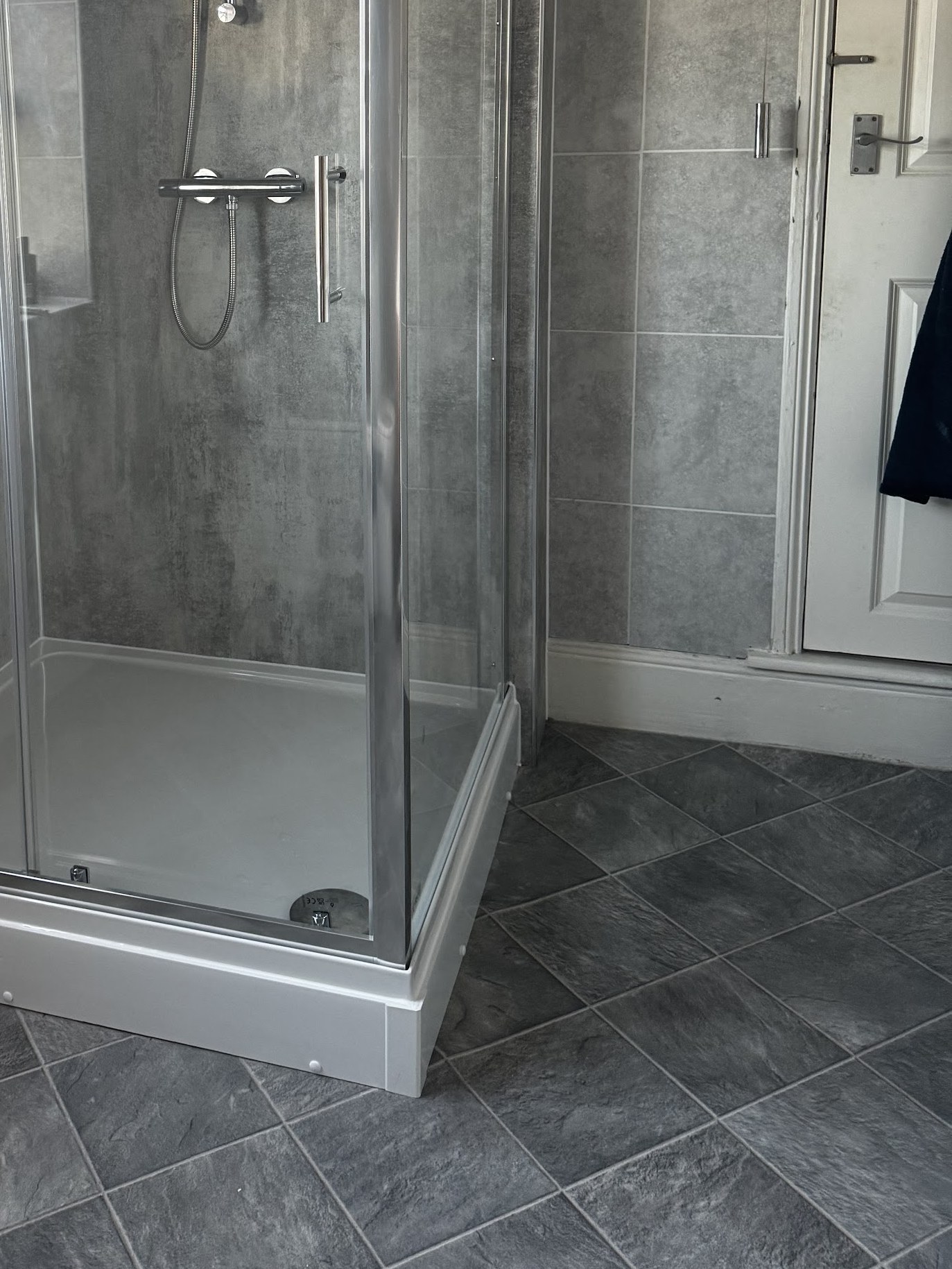 The finished shower enclosure with glass doors on a white tray and grey wall panels
