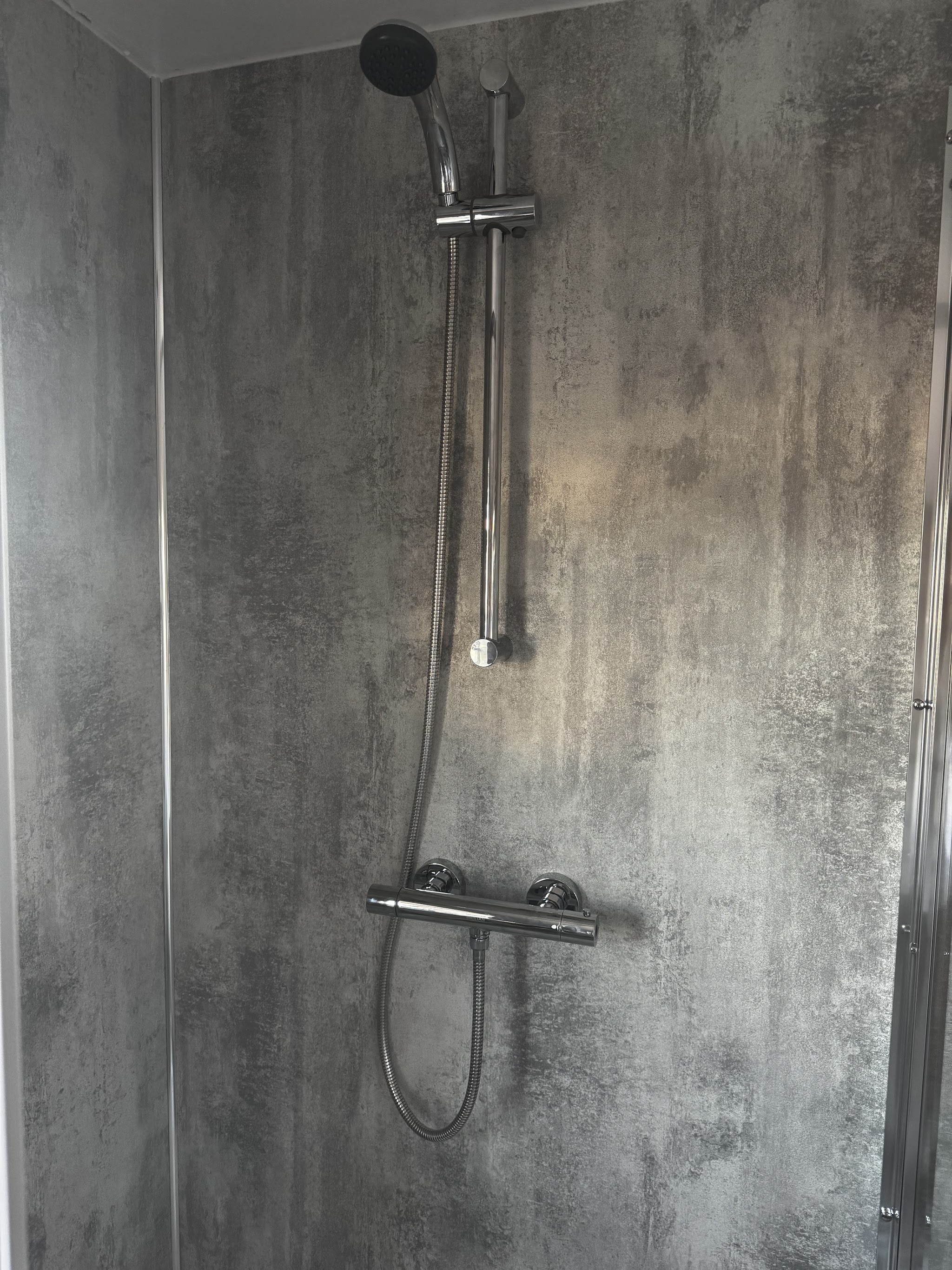 The new shower: grey stone-effect wall panels, a chrome thermostatic bar valve and riser rail